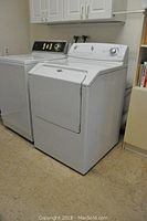 Front and side view of white Maytag Atlantis dryer next to washer