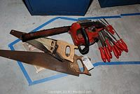 Lot showing Homelite Super 2 chainsaw, two hand saws with wooden handles, and metal files with red handles.