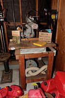 Wide view of radial saw setup on wooden bench with manual and saw blades box visible