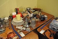 Full view of assorted vintage kitchenware items including copper pots, waffle iron, molds, tins, salad bowls, and small appliances.