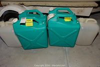 Six water containers arranged in a row showing four teal 6-gallon containers and two white containers.