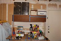 Wide shot displaying a collection of automotive care products including sprays, lubricants, and cleaners on a workbench with two flashlights in front.