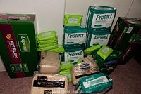 Overview of the lot showing multiple packages of Depend Fit-Flex and Protect adult protective underwear along with individual wrapped baby wipes.
