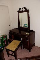 Full view of the vintage wooden vanity with mirror and bench in room corner