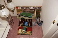 Photo showing the lot contents including backgammon set, table tennis paddles, dominoes, football game box and helicopter box.
