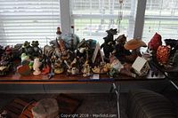 Wide view of table filled with various garden decor items including gnomes, birdhouses, and frogs