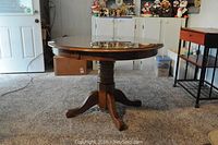 Full view of round oak pedestal table with three-legged base and glass top, showing proportional size and overall condition.