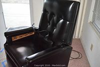 Front angle view of the black vinyl Niagara Cyclo-Massage recliner chair showing padded seat, tufted backrest and armrests with control switches.