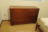 Front view of the dresser showing six closed drawers in a warm brown wood finish.