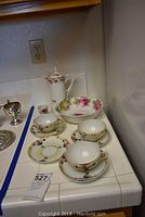 Full view of set including hot chocolate pot, egg cup, cups, saucers, and bowl on white tiled counter.