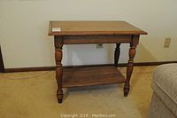 Front view of the wooden side table showing the rectangular top and lower shelf with turned legs.
