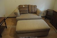 Front view of beige chair and ottoman in room with side tables