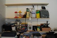 Wide view showing shelves with garden sprayers, feeders, garden hose, plant pots, garden light box, and plant food.