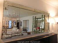 Front view of large rectangular sectional mirror mounted on wall in living area
