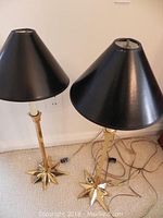 Pair of vintage brass starburst desk lamps standing side by side with black conical shades attached, showing overall height and style.