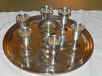 Tray with six cordial cups and small urn arranged on white cloth