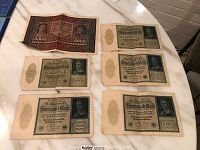 Five vintage paper banknotes laid out on a table: four German 10000 Mark Reichsbanknotes, and one Polish 5000 Marka Krajowa note.