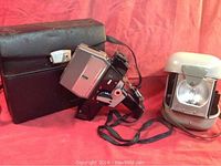 Vintage Bolex 160 Macro Zoom Super 8 MM camera with attached strap, accompanied by black leather carrying case and separate flash bulb with gray plastic case.