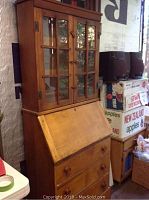 Front view of maple secretary desk with glass hutch and drawers