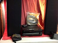 Overall view showing two tower speakers flanking stacked audio components on a red backdrop