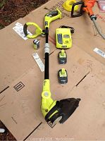 Full view of the Ryobi 18V weed wacker with two batteries and charger laid out on cardboard.