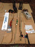 All gear laid out including boots, fishing rods, bows, and tackle box