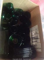 Box containing multiple green glass plates/saucers and several glasses.