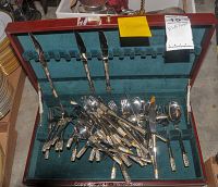Opened wooden case showing knives, forks and spoons with gold and silver decorated handles.