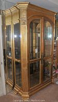 Front view of gilt curio cabinet with glass panels and ornate carvings
