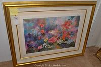Framed colorful art print showing hummingbirds and flowers in various colors, with a gold frame and dual mats.