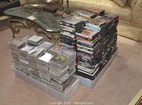 Long shot of two large stacks of DVDs at right and one large bin of CDs at left on carpeted floor