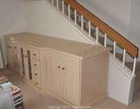 Front view of large custom wooden media cabinet with drawers, solid and glass-paneled doors, brass knobs, and worn top surface.