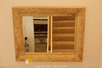 Front view of wall mirror showing rectangular reflective surface and textured rustic frame.