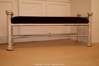 Foot bench with cream-colored frame and dark upholstered seat showing normal wear.