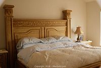 Front view of king size bed frame showing detailed carvings on headboard and large posts