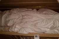 Photo showing white down comforters folded and packed inside a large box or trunk.