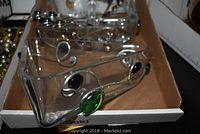 Small clear glass dish with large green stone on side and silver accents.