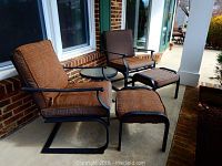 Photo of two metal framed patio chairs with brown mesh cushions and two matching ottomans on a porch.