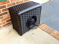 Side angle showing rectangular hose reel box in brown faux wicker pattern with attached hose coiled on side.