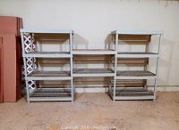 Front view of plastic shelving unit with three sections visible. Each side section has four shelves, center section has two shelves. Gray color, open grid shelving.