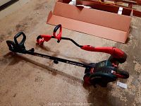 Black & Decker Edge Hog electric yard tool with ergonomic handles and edging base, laid on concrete floor.