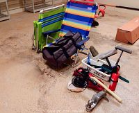 Three Rio Beach high back beach chairs and assorted car accessories including electric polisher, trailer hitch, fire extinguisher, and car washing brushes arranged on floor.