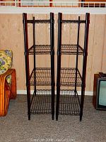 Pair of black coated wire shelving units side by side against wood panel wall, showing front and side angles