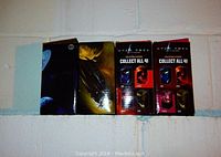 Four boxed Star Trek 2008 commemorative collectible glasses are shown side by side stacked horizontally on a basement shelf, featuring packaging artwork of the characters and promotional text.