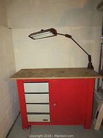 Front view of Hirsch work table showing 4 drawers, cabinet door and attached work lamp