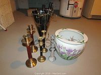 Overview photo showing three pairs of candlesticks made of brass with wood accents and polished marble, a black metal umbrella stand with brass details, and a ceramic planter with iris painting.