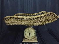 Side view of the antique wicker basket cradle lifted off the base of the metal baby scale.