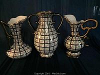 Three Henri Bequet Quaregnon vases photographed together, showing their shape, size, and decorative pattern with floral designs and gold handles.