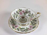 Tea cup and saucer front view showing floral design and royal insignia inside cup.