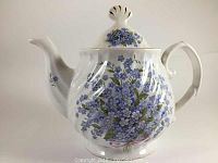 Front and side view of the Royal Caldone Forget Me Not floral tea pot with blue flowers and pink ribbon design.